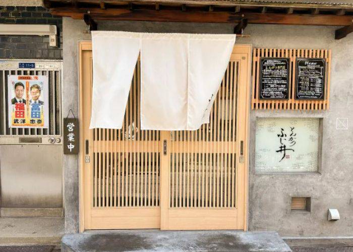 The traditional exterior of Tonkatsu Fujii, featuring a slatted sliding door and noren curtain.